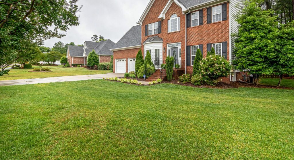 Two-story brick house behind a wide green front lawn
