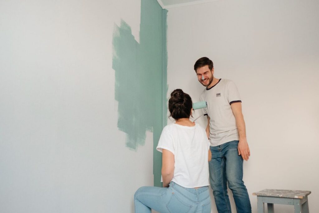Couple laughing while they paint a wall of their home