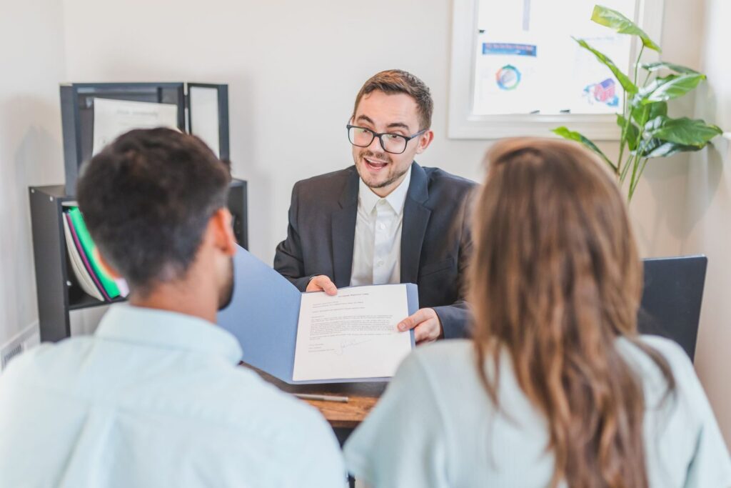 Loan officer showing a loan document to a couple across the desk