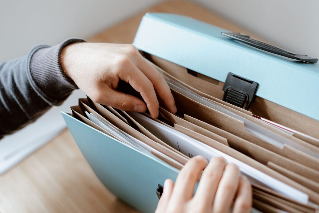 Hands leafing through papers in an expanding file organizer
