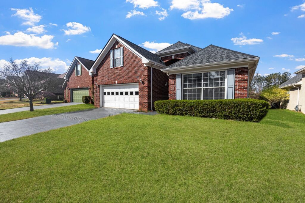 Brick home with a trimmed hedge, driveway and lawn on a sunny day